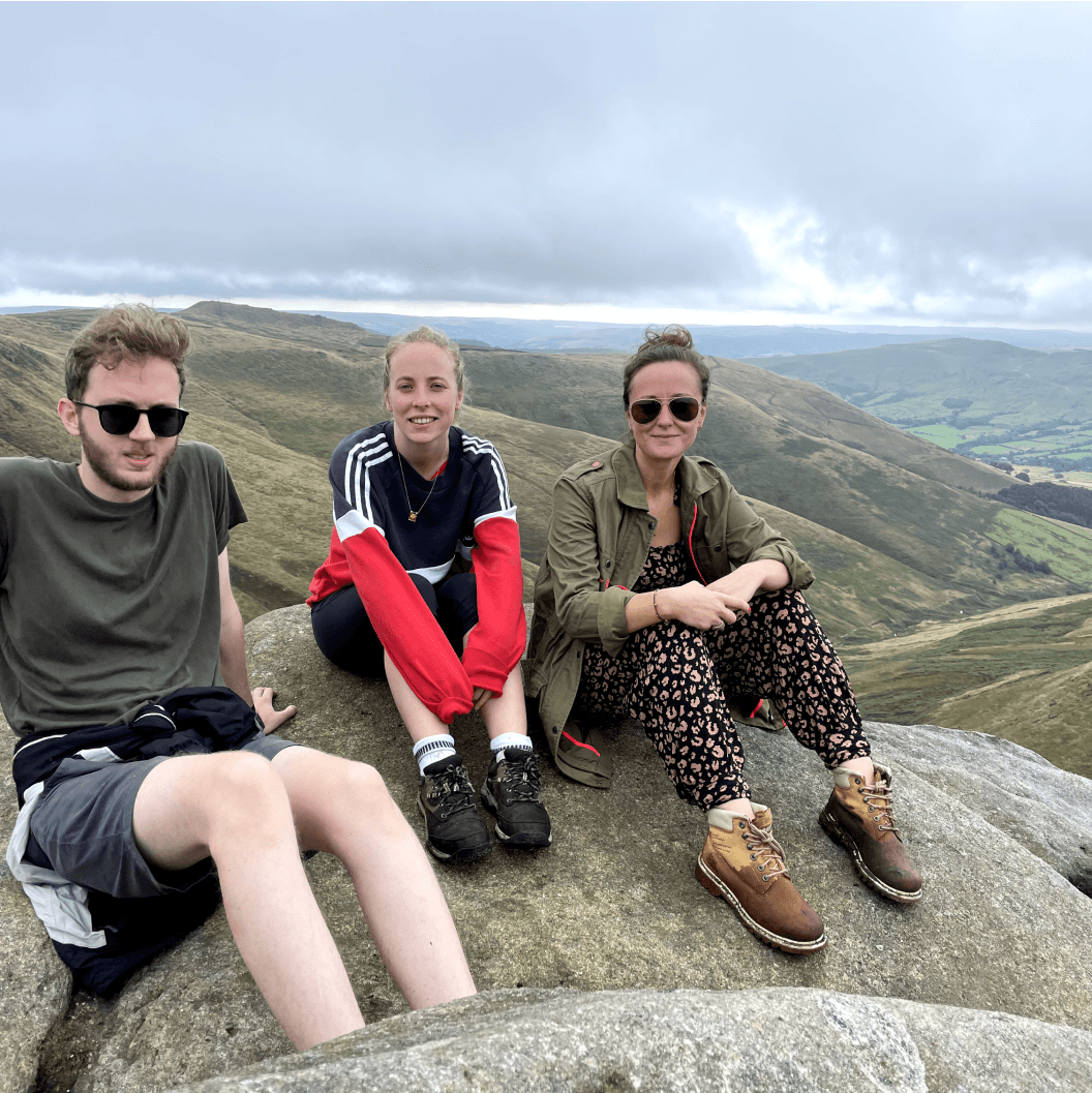 Members of the team near a cliff with mountains far away